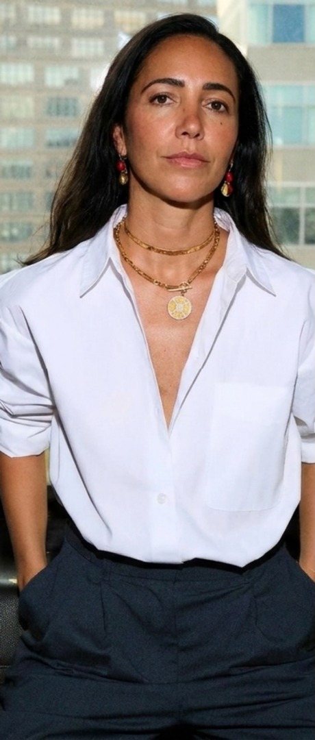 Portrait of Virginia Lemes in a white shirt with layered gold necklaces